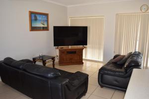 Port Noarlunga克里斯蒂斯海马假日联排别墅的客厅配有黑色真皮沙发和平面电视。
