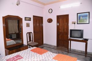 海得拉巴anjani mansion的一间卧室配有一张床、一台电视和一面镜子
