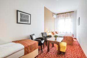 克罗梅日什Hotel U Zlatého kohouta的酒店客房带两张床和一张桌子以及椅子。