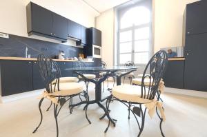 蒙斯La Maison de la Duchesse de la Vallière - Parking privé gratuit的厨房配有玻璃桌和四把椅子