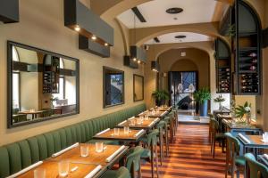 罗马旧金山酒店的一间带木桌和绿色座椅的餐厅