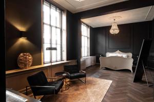WarmondBoutique Hotel Huys Oud Teylingen的客厅设有黑色墙壁、沙发和椅子