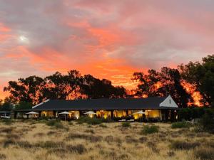 BritstownSweetfontein Boutique Farm Lodge的一座位于田野中间的建筑,享有日落美景