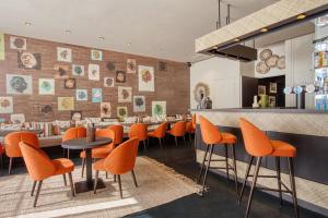 里尔Boa Hotel - BW Signature Collection - Lille Centre Gares的一间设有橙色椅子的餐厅和一间酒吧