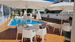 福尔内利斯Hostal S'Algaret的游泳池旁带桌子和遮阳伞的天井