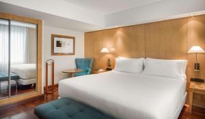 马德里帕萨奥哈瓦那NH酒店的酒店客房带一张大床和一把椅子