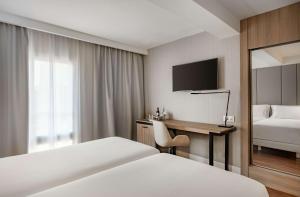 马德里帕萨奥哈瓦那NH酒店的酒店客房配有一张床、一张书桌和一台电视。