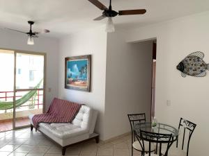 瓜鲁雅Apartamento Enseada的客厅配有白色沙发和玻璃桌