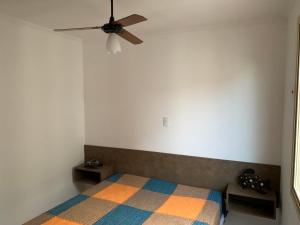 瓜鲁雅Apartamento Enseada的一间卧室配有一张带吊扇的床
