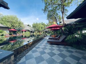 清迈Na Mantra Resort的一个带桌子和遮阳伞的游泳池的度假酒店