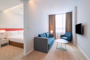 新山Holiday Inn Express & Suites Johor Bahru, an IHG Hotel的配有床、椅子和桌子的酒店客房