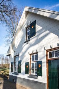 HaarleHerberg de Pas的白色的房子,设有绿色的门和窗户