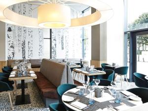 伦敦伦敦温布利诺富特酒店的一间带桌椅和大吊灯的餐厅