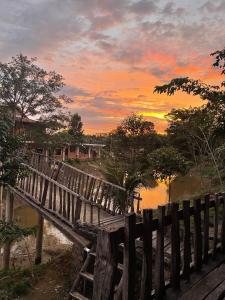 Quan TomRice straw Green lodge- resort的一条木桥,在河上,日落