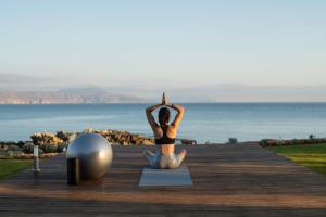 PetresAn intimate Villa Resort- Right on the beach, by ThinkVilla的坐在木板路上的瑜伽姿势中的女人