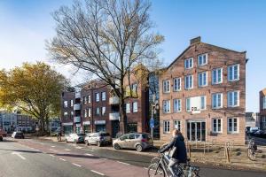 皮尔默伦德City Trip Hostels Amsterdam-Purmerend的骑着自行车沿着城市街道的女人