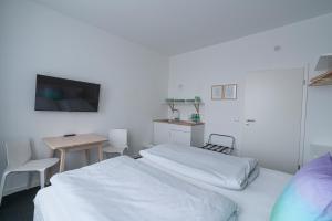 莱比锡BIG MAMA Leipzig的一间卧室配有两张床、一张桌子和一台电视。