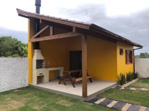 因比图巴Casa em Ibiraquera próxima a praia do Rosa的庭院中一间带壁炉的黄色小房子