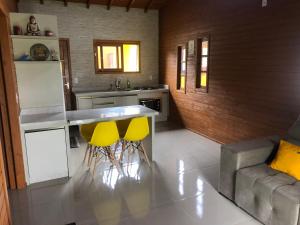 因比图巴Casa em Ibiraquera próxima a praia do Rosa的厨房配有2张黄色吧台凳和1个柜台