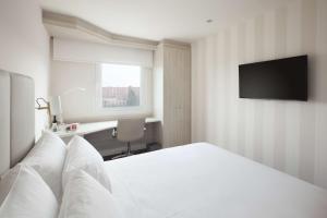 马德里巴拉哈斯机场NH酒店 的卧室配有白色的床和电视。