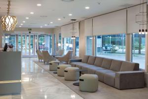 马德里巴拉哈斯机场NH酒店 的大堂配有沙发、椅子和窗户。