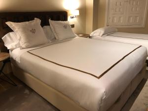纳瓦尔卡内罗Hotel Boutique Casa del Comendador的配有2张床铺的酒店客房,提供白色床单和枕头