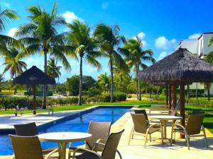 普拉亚多Condominio Iberostate的一个带桌椅的度假村游泳池,并种植了棕榈树