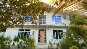 幸福岛Dhonveli Inn, Bandidhoo的白色的房子,拥有蓝色的窗户和树木