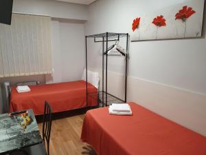 洛格罗尼奥Pensión El Espolón的一间设有两张红色床单和一张桌子的房间