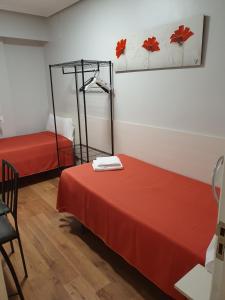 洛格罗尼奥Pensión El Espolón的一间设有两张红色床单和镜子的床的房间