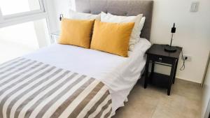 圣罗莎Poas - Alquiler temporario的一间卧室配有一张带黄色枕头和桌子的床