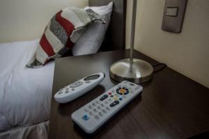 塔尔卡Hotel Capelli Express的两个遥控器坐在床边的桌子上