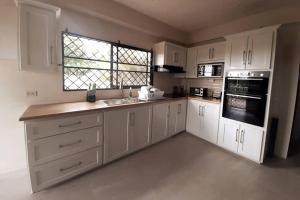 ArimaMango Vert House的厨房配有白色橱柜、水槽和窗户。