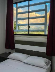 阿瓜奇卡Sagrado Hotel的卧室设有窗户、一张床和一个枕头