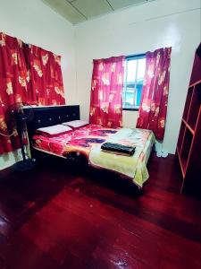 昆达桑Kinabalu Valley Guesthouse的卧室配有红色窗帘的床