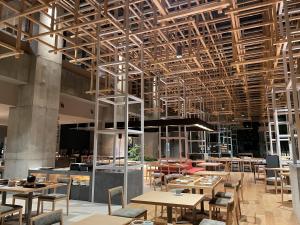 别府AMANEK Beppu YULAｰRE的餐厅设有木桌、椅子和天花板。