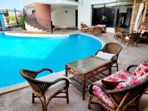 马萨阿拉姆Oasis marsa alam的游泳池旁设有椅子和桌子