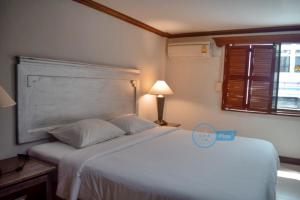 芭东海滩丹戎旅馆的卧室配有白色的床和窗户。