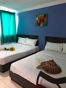 古晋加帛酒店的一间设有两张床和蓝色墙壁的客房