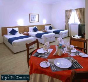 沙迦阿尔塞夫酒店的酒店客房设有两张床和一张带红色桌布的桌子。