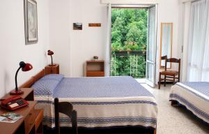 BognancoAlbergo Ristorante Regina的一间卧室设有两张床、一张桌子和一个窗口