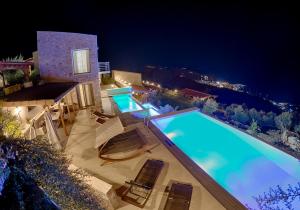 斯基亚索斯镇Sky Sea Resort Skiathos的一个带椅子的游泳池,晚上有房子