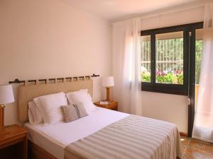 帕尔斯Casa adosada en Platja de Pals by Apartaments Golf的一间卧室配有一张带白色床单的床和一扇窗户。