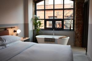 曼彻斯特Leven Manchester的一间卧室设有一张床、浴缸和一个窗口