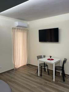 巴里海市蜃楼住宿加早餐旅馆的一间设有白色桌椅和电视的客房