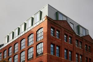 曼彻斯特Leven Manchester的一座带金属屋顶的红砖建筑