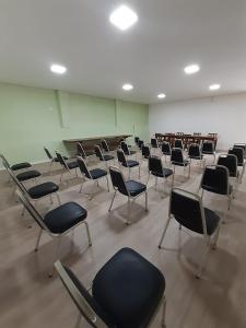 瓜鲁柳斯Ipê Guaru Hotel的教室里带椅子和书桌的房间