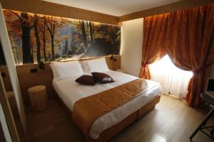 尚波吕克培缇图娜琳酒店的卧室配有一张大床,墙上挂有绘画作品