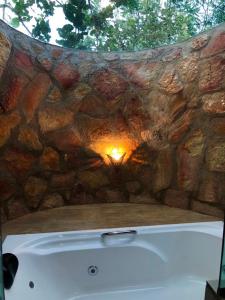 巴西利亚Villa Triacca Hotel Vinícola & Spa的石质浴缸前的石墙,配有浴缸