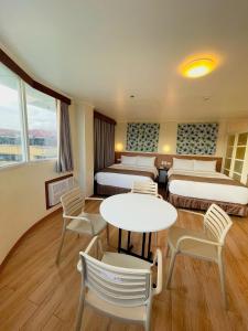 黎牙实比Hotel Sentro Legazpi的酒店客房带两张床和一张桌子以及椅子。